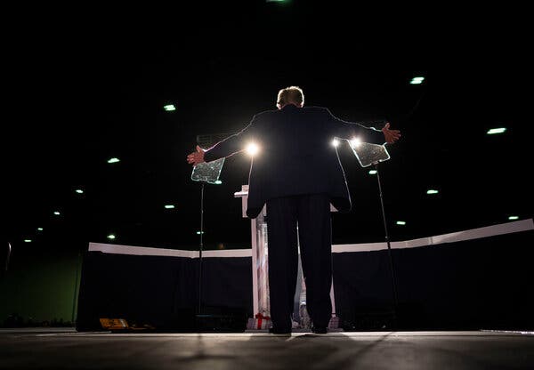 A low shot of Mr. Trump facing outward, toward a crowd, with his arms spread. 