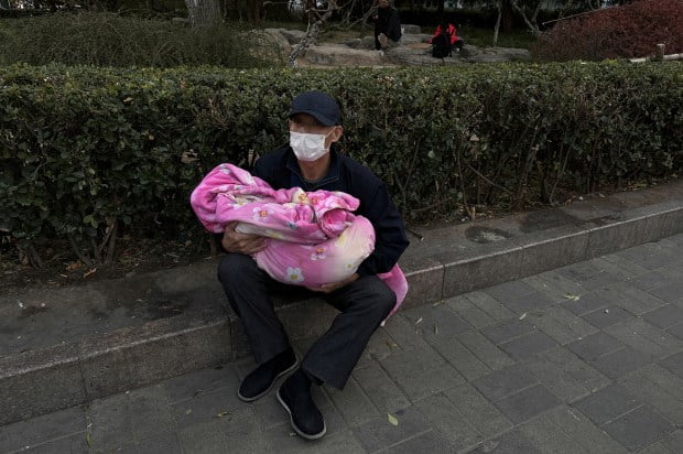 man carrying child sits outside 862357779 china and world panic over white lung syndrome in children